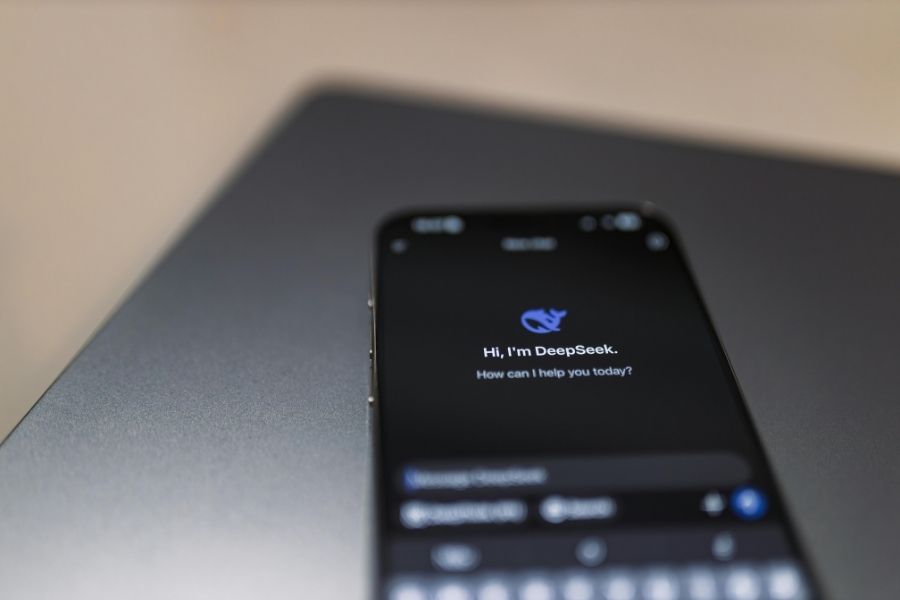 A smartphone lying on a dark laptop displaying the mobile user interface of DeepSeek.