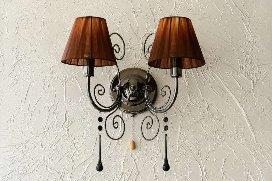 Elegant twin wall lights featuring dark brown fabric shades mounted on a textured white wall.